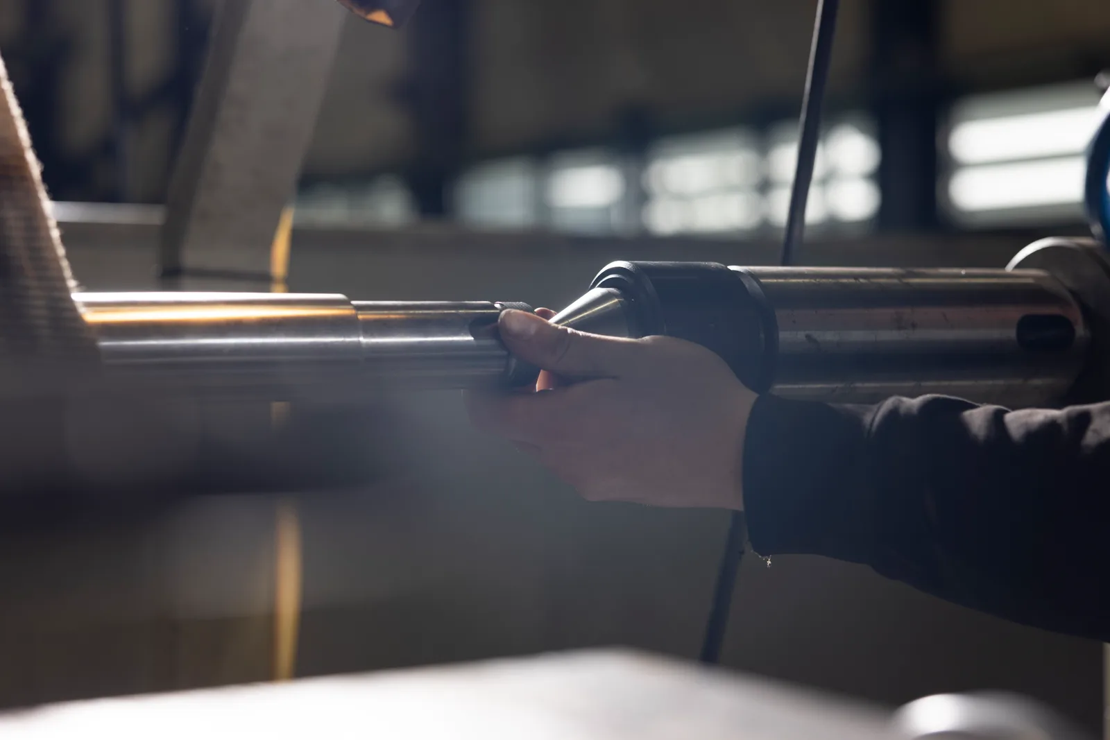 Eine Hand an einer Metallwelle in einer Maschine