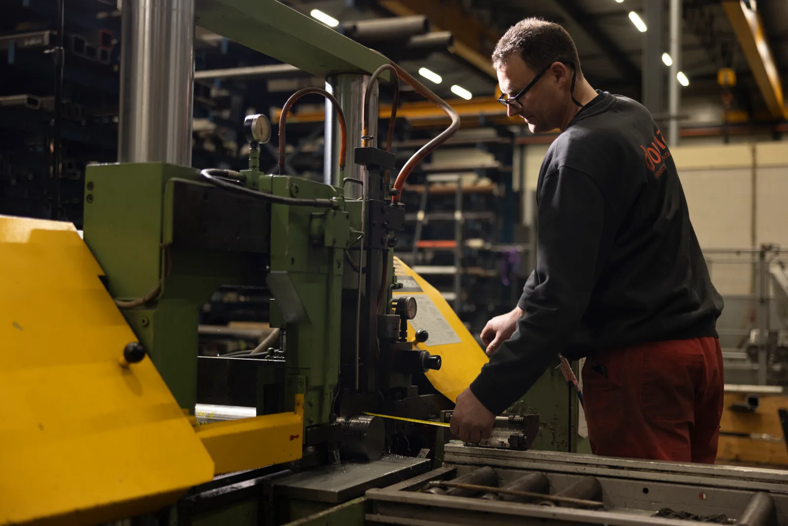 Vakman van Douna aan het werk bij een metaalzaag in de werkplaats.