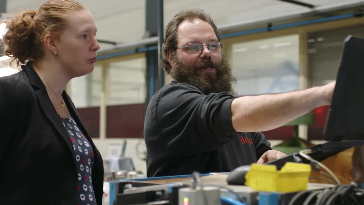 Two employees discuss a technical setup in the workshop