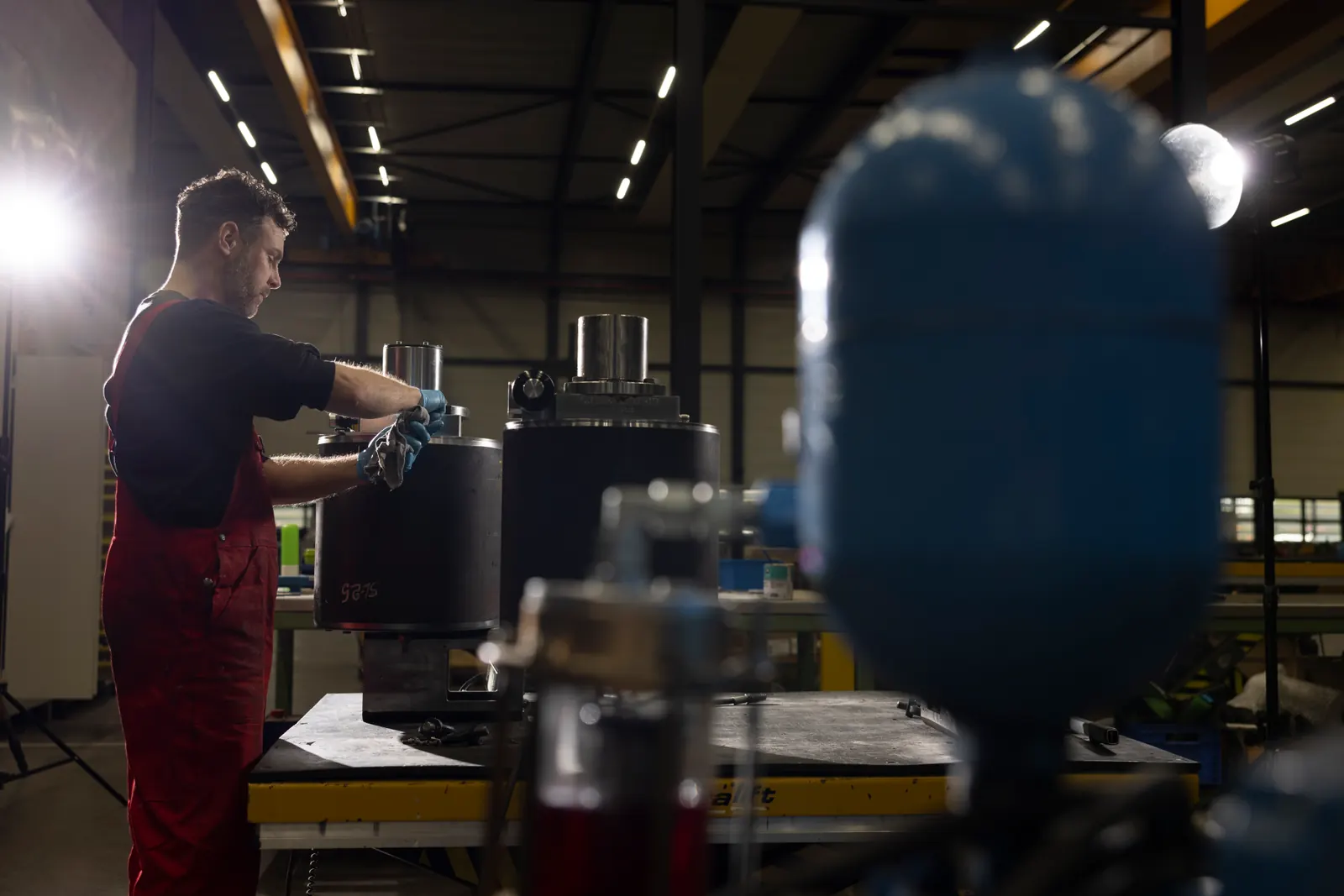 A worker fits a part to a large assembly on the workbench