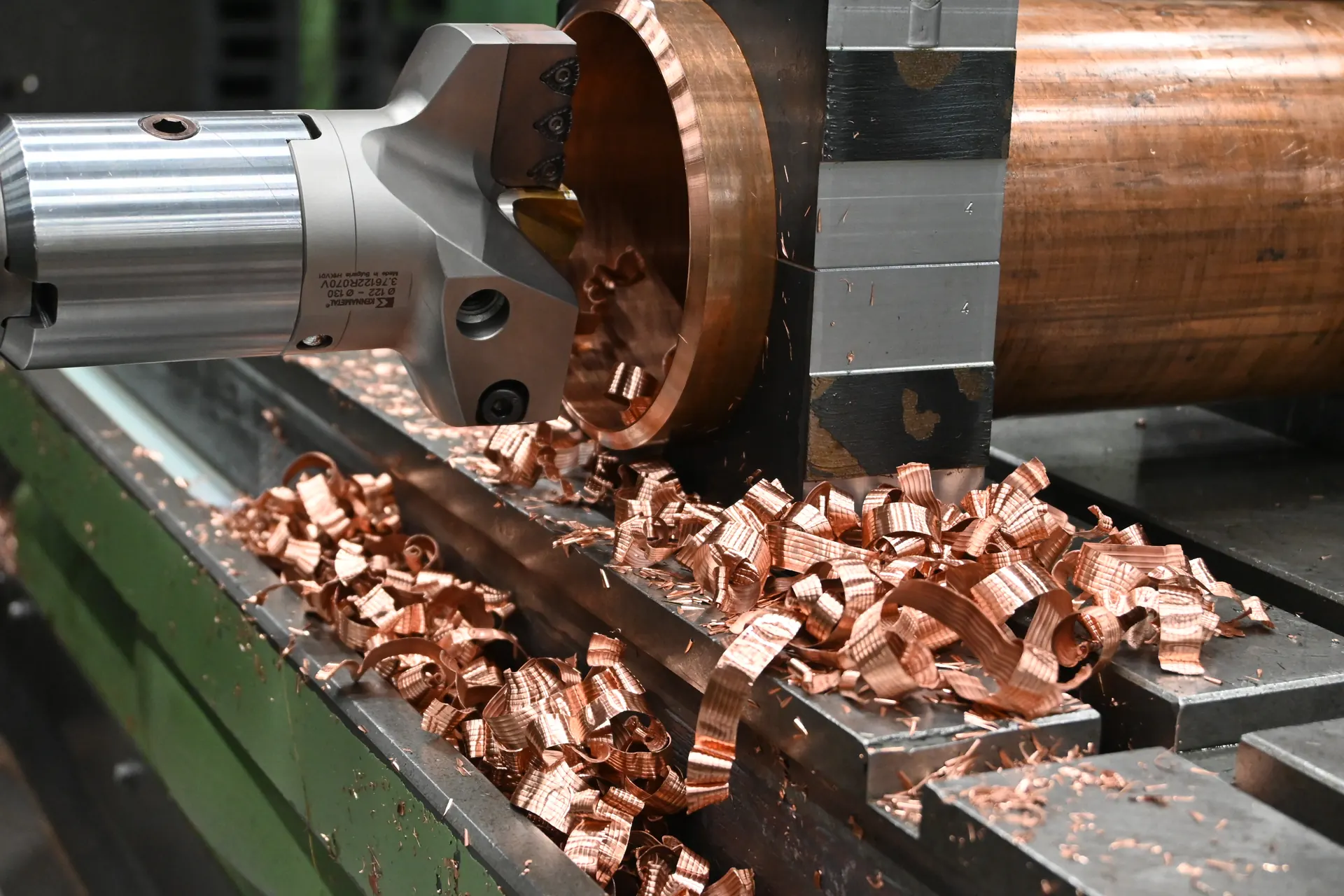 Kottergereedschap bij een opgespannen cilindrisch werkstuk met metaalspanen op het machinebed.